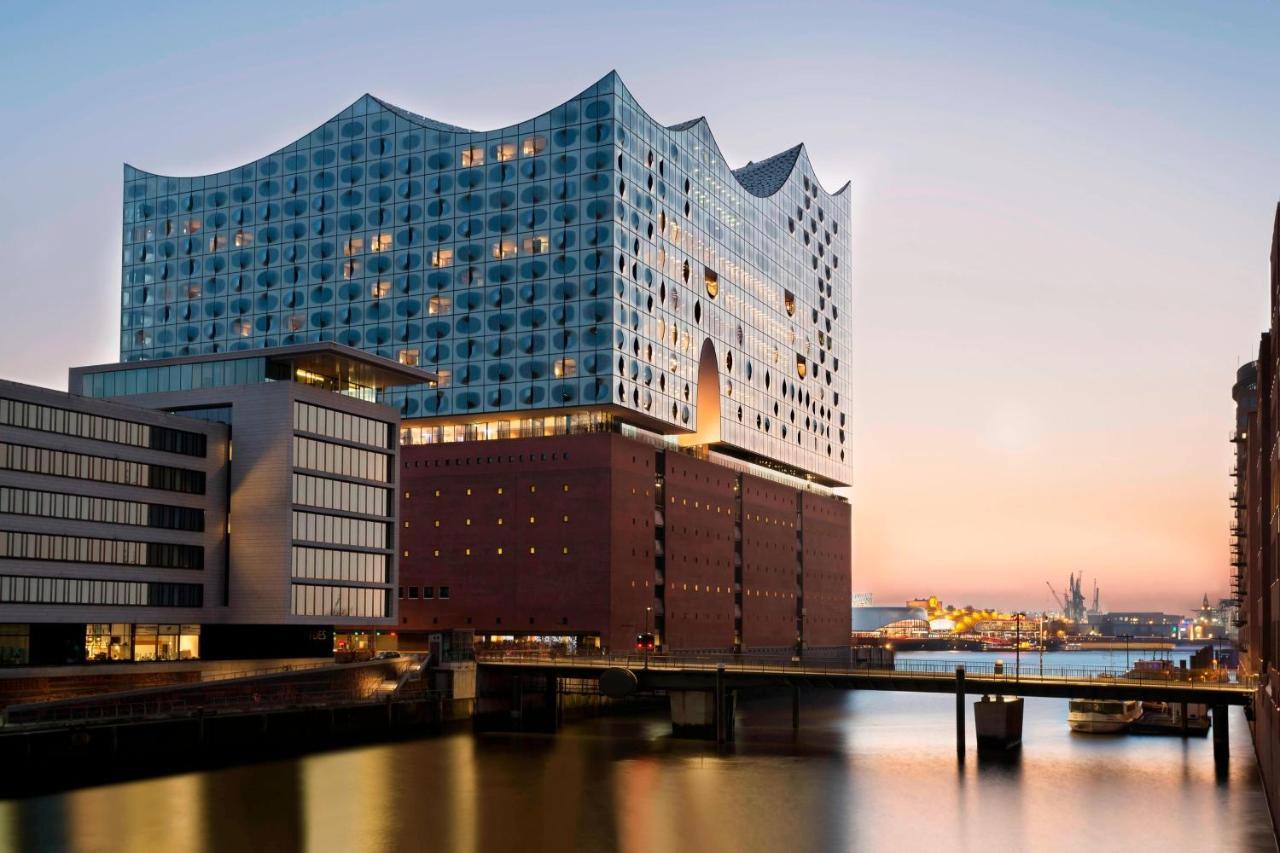 The Westin Hamburg Elbphilharmonie Hotell Eksteriør bilde The photo shows a modern architectural structure located by a body of water, possibly a river or canal. The building features a unique wavy roofline and a facade made of glass and other materials, giving it a contemporary look. It is likely a cultura