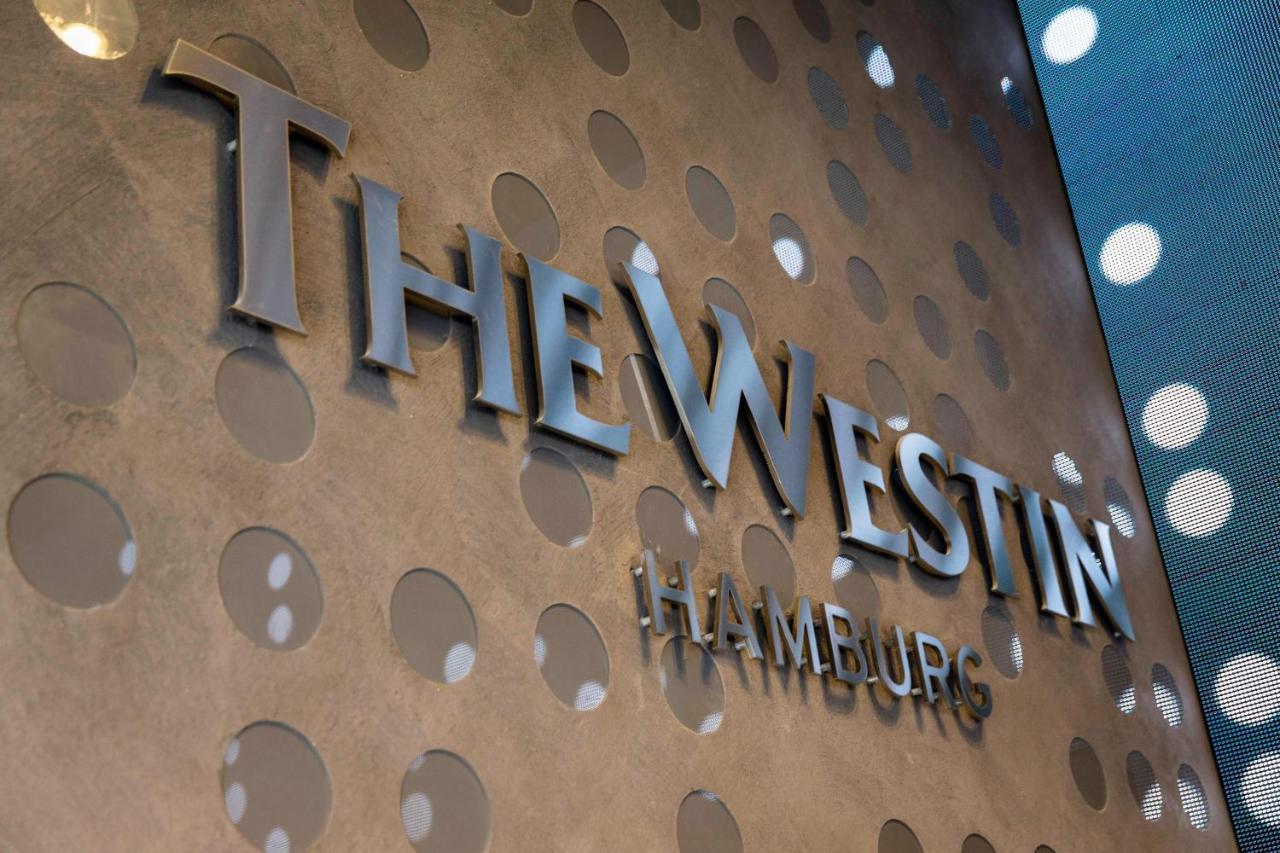 The Westin Hamburg Elbphilharmonie Hotell Eksteriør bilde The image shows a decorative wall featuring the logo of "The Westin Hamburg." The logo is prominently displayed in a sleek, silver font. The background has a textured surface with circular patterns, adding a modern and elegant touch to the overall ap