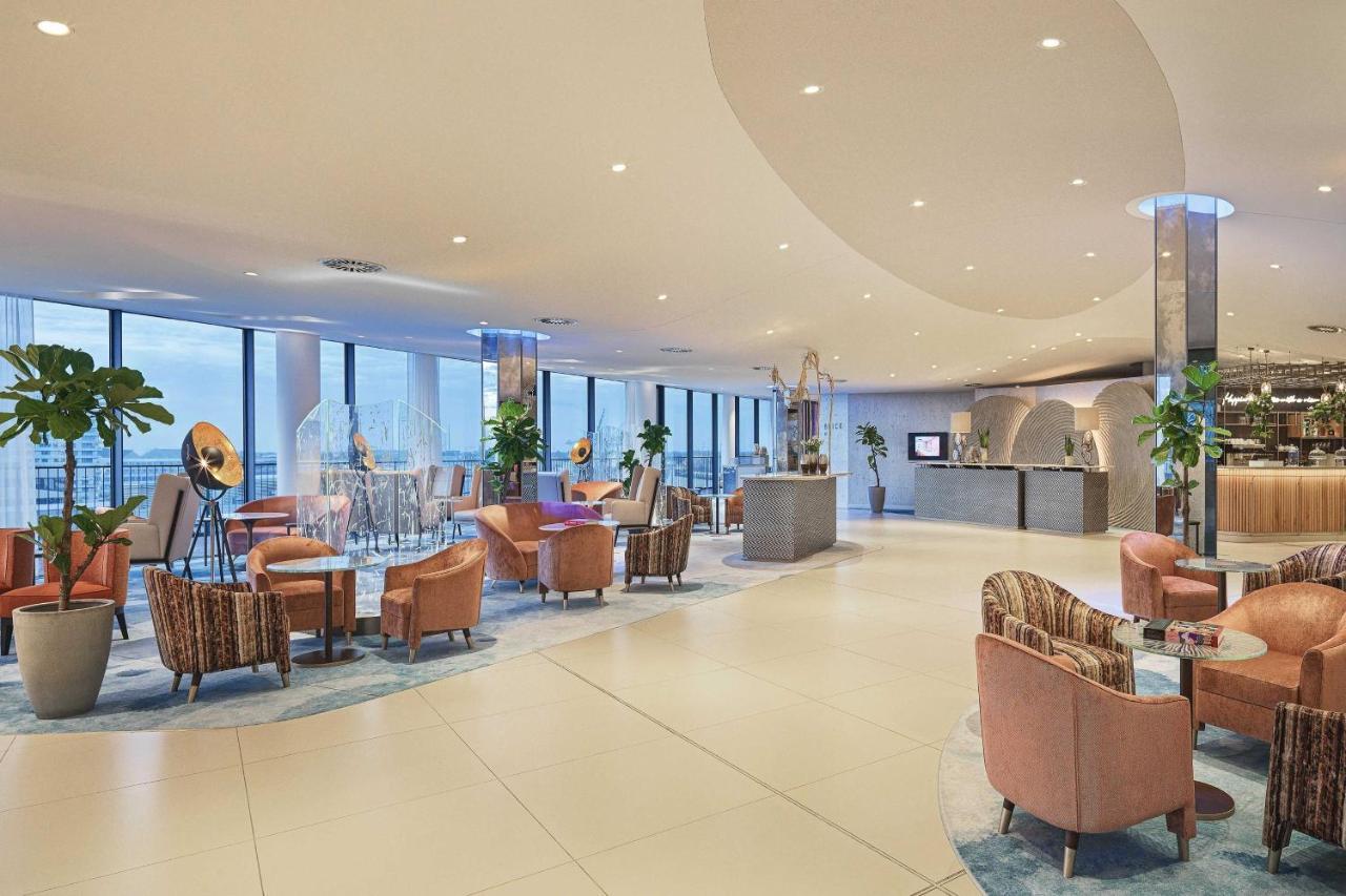 The Westin Hamburg Elbphilharmonie Hotell Eksteriør bilde The image shows a modern, stylish interior, likely from a hotel or upscale lounge. The space features large windows that allow natural light to flood in, offering a view of the outside. There's a mix of comfortable seating arrangements, including sev