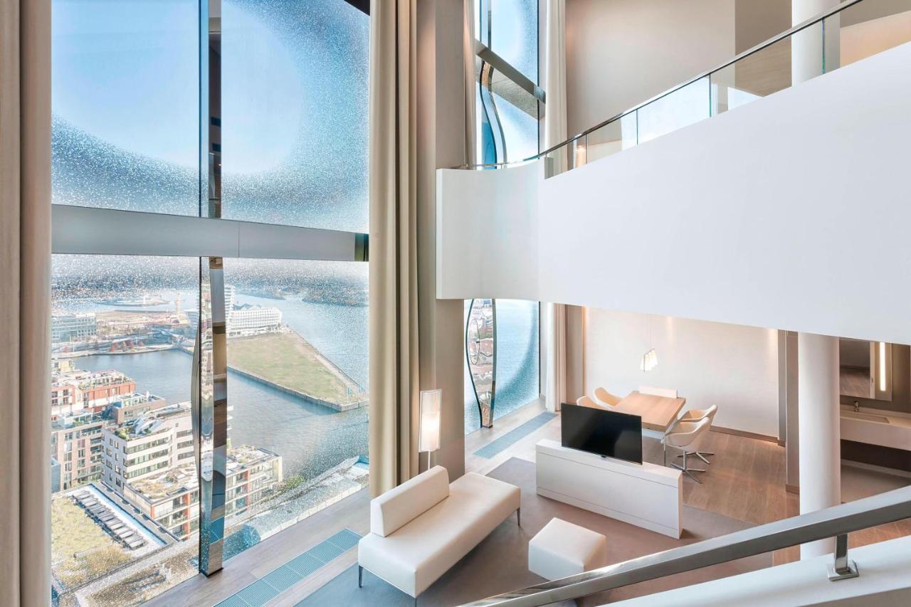 The Westin Hamburg Elbphilharmonie Hotell Eksteriør bilde The photo showcases a modern, stylish interior of a multi-level living space. It features large, floor-to-ceiling windows that provide a panoramic view of the surrounding landscape and water. The decor is minimalist, with a predominantly white color 