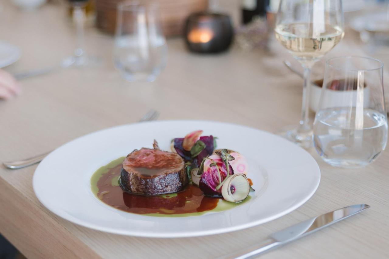 The Westin Hamburg Elbphilharmonie Hotell Eksteriør bilde The photo shows a beautifully presented plate of food, featuring a piece of meat, likely a fillet, sliced neatly and arranged at the center. It is accompanied by a rich, glossy sauce that pools around the meat. Surrounding the meat are colorful edibl